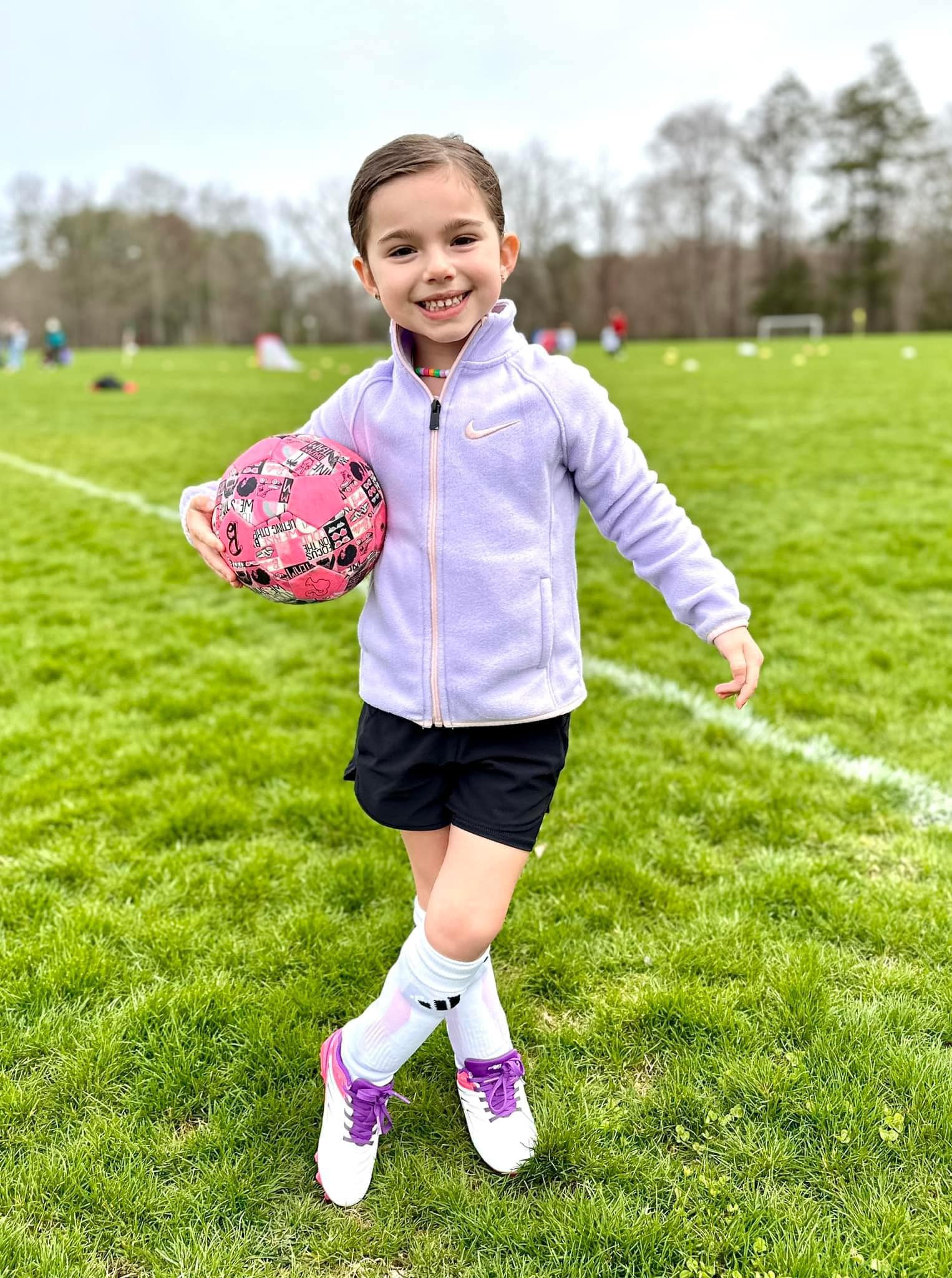 Pre K soccer player holding a ball and curtseying 